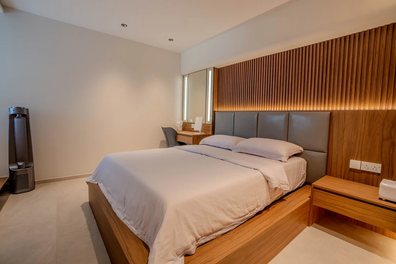 Modern master bedroom design featuring warm wooden panel accents and cozy lighting.