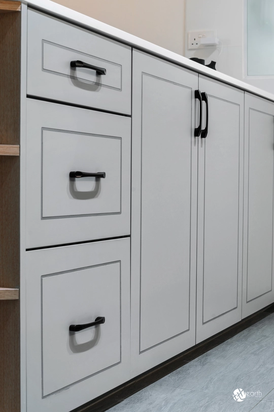 Close-up of gray shaker-style kitchen cabinet design with black handles.