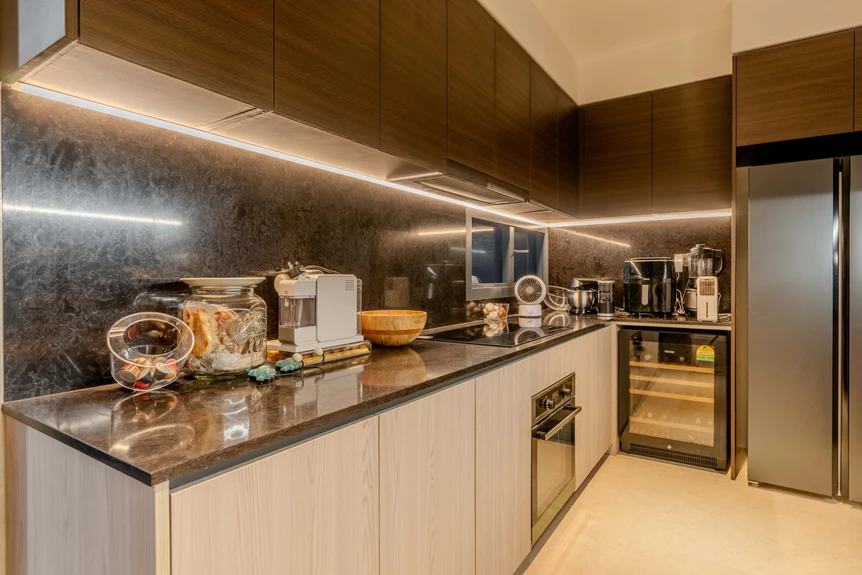 Functional kitchen design with wood cabinets, black marble finishes, and stainless steel appliances.