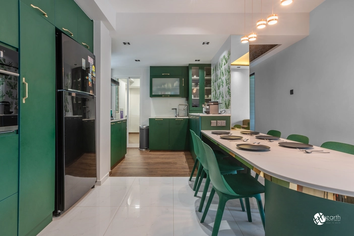 Modern kitchen dining area with green chairs and a white marble tabletop.