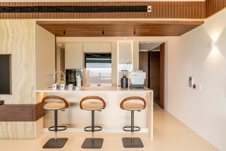 Luxurious open kitchen design with a marble island, wooden ceiling accents, and stylish bar stools.