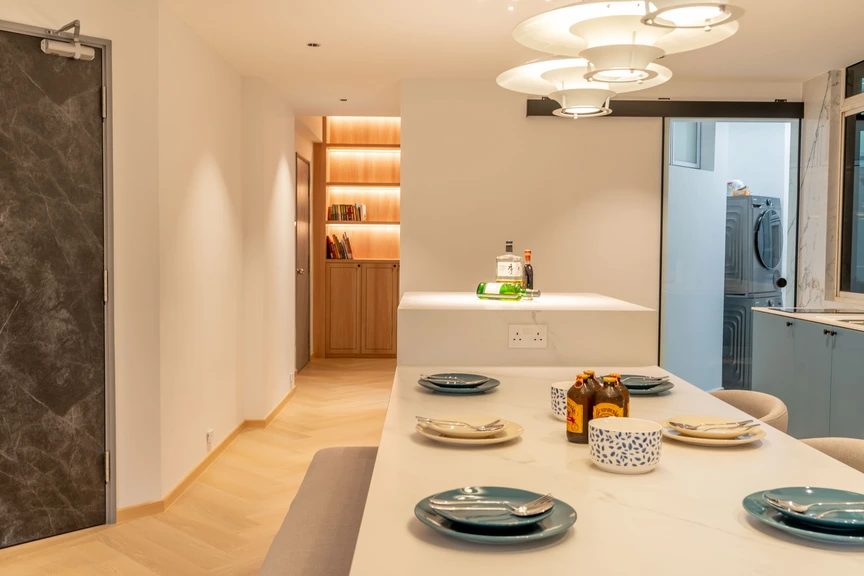 Stylish kitchen with an extended dining table, minimalist decor, and warm wooden flooring.