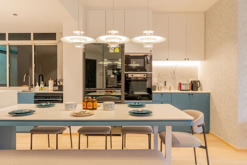 Modern open-concept kitchen with soft green cabinets, a sleek island, and elegant pendant lighting.