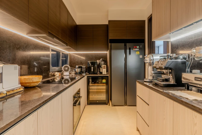 Modern kitchen with warm wooden cabinets, sleek black countertops, and under-cabinet lighting.