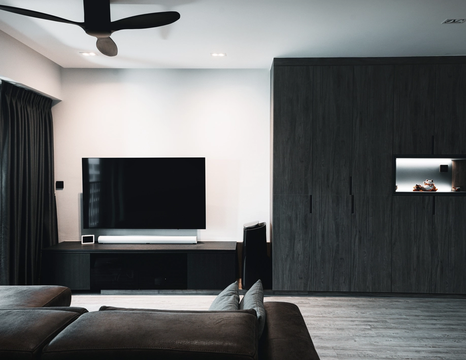 Modern living room with dark tones, integrated lighting, and minimalist decor.