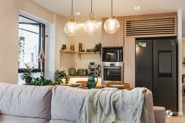 Living room design featuring a cozy sofa setup overlooking a minimalist kitchen and dining area.